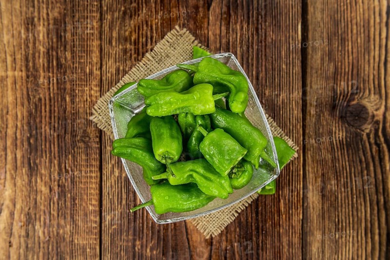 Raw Pimientos on rustic wooden background as close-up shot