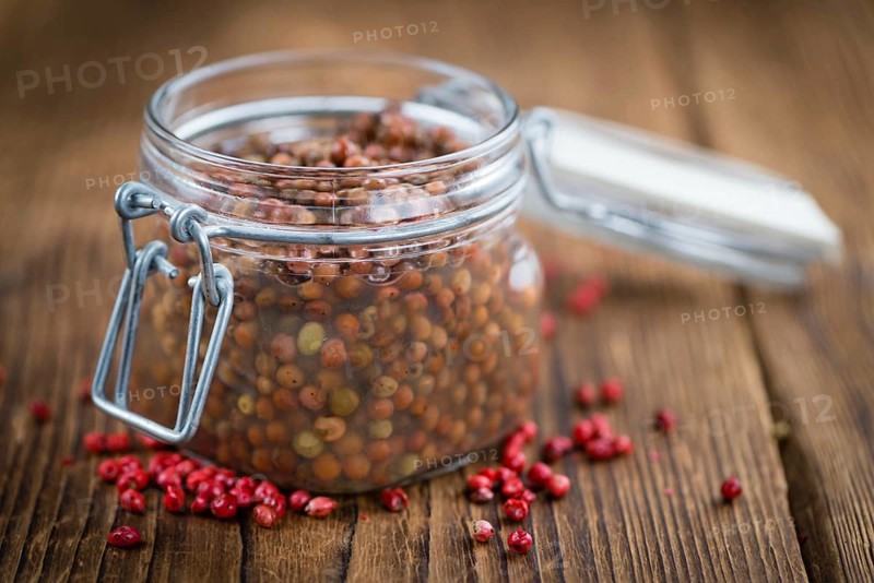 Preserved Pink Peppercorns on a vintage background as detailed close-up shot, selective focus