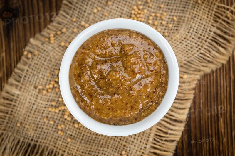 Homemade Sweet Mustard on an wooden table (selective focus) as detailed close-up shot