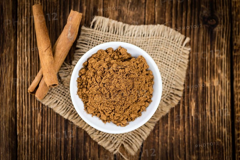 Cinnamon Powder as high detailed close-up shot on a vintage wooden table (selective focus)