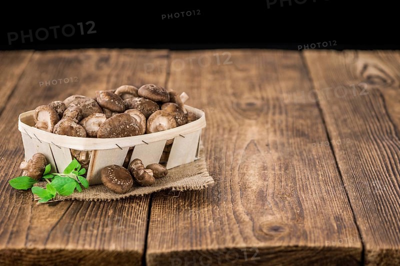 Raw Shiitake mushrooms as high detailed close-up shot on a vintage wooden table, selective focus