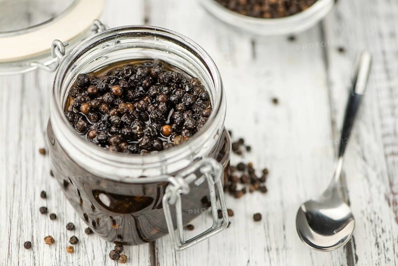 Preserved black Peppercorns on wooden background, selective focus, close-up shot