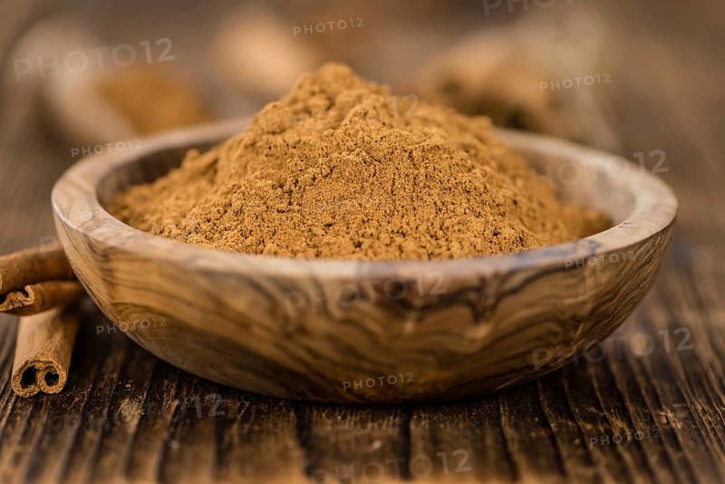 Cinnamon Powder as high detailed close-up shot on a vintage wooden table (selective focus)