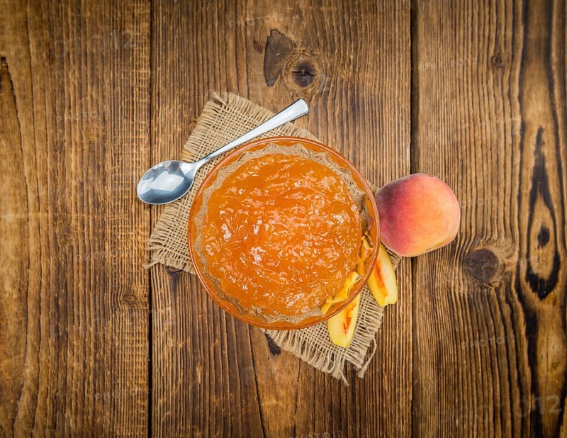Peach Jam on an old wooden table as detailed close-up shot, selective focus