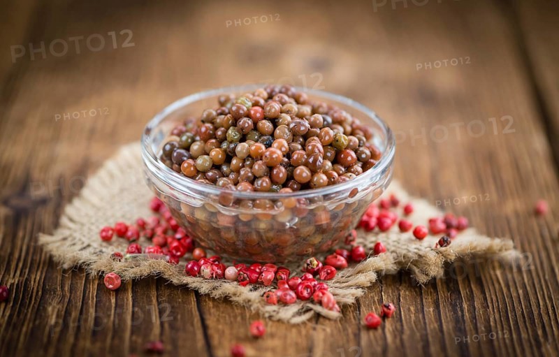 Preserved Pink Peppercorns on a vintage background as detailed close-up shot, selective focus