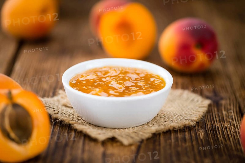 Apricot Jam on an old wooden table as detailed close-up shot (selective focus)