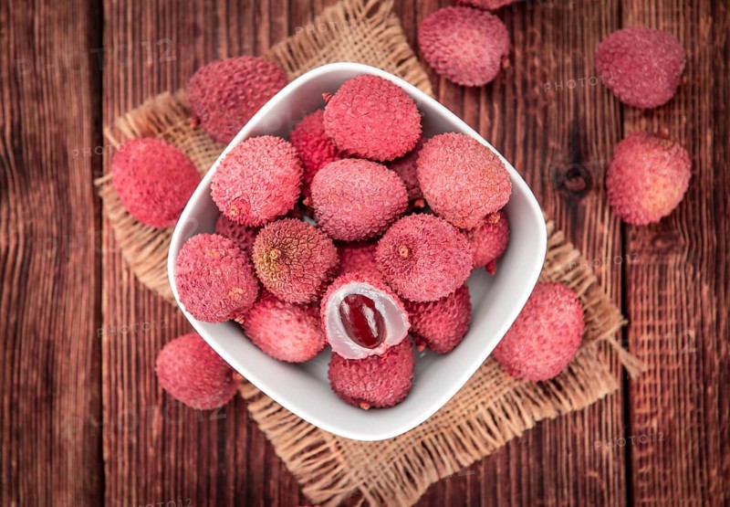 Litchis on rustic wooden background (close-up shot)