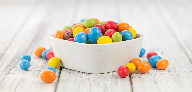 Cocolate coated Peanuts on rustic wooden background (close-up shot)