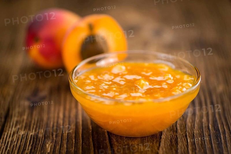 Apricot Jam as high detailed close-up shot on a vintage wooden table (selective focus)