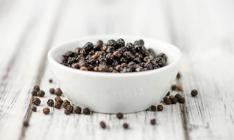 Preserved black Peppercorns on a wooden table as close-up shot