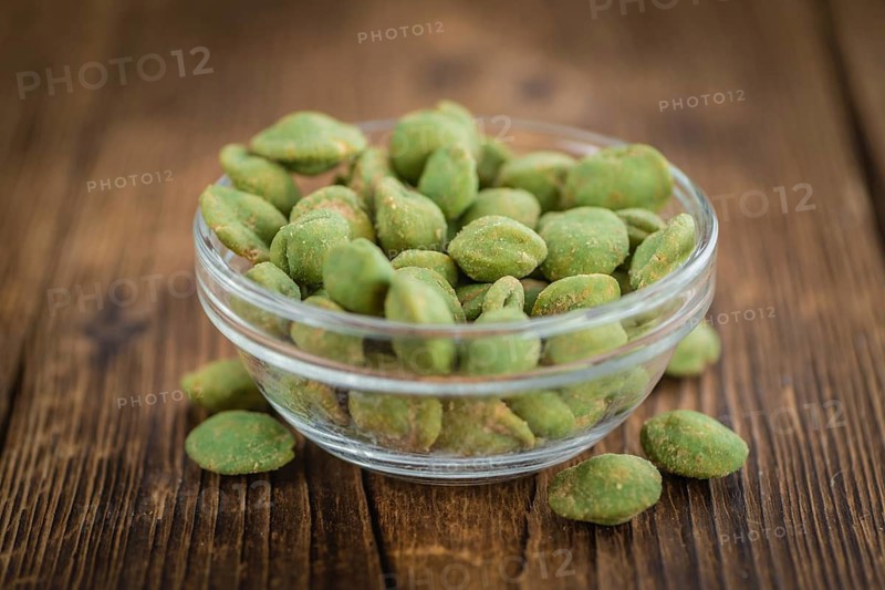 Peanuts (with Wasabi flavor) on an old wooden table as detailed close-up shot (selective focus)