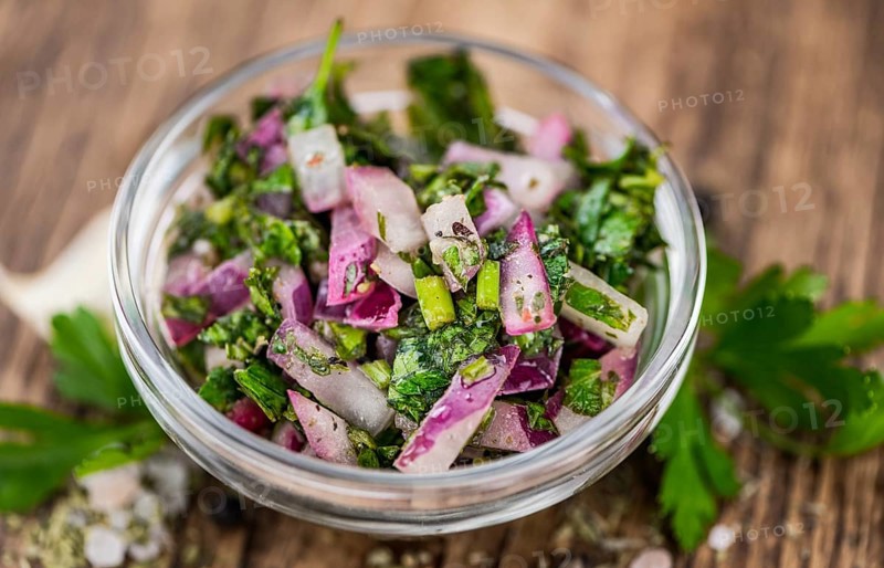 Healthy homemade Chimichurri on a wooden table as detailed close-up shot (selective focus)