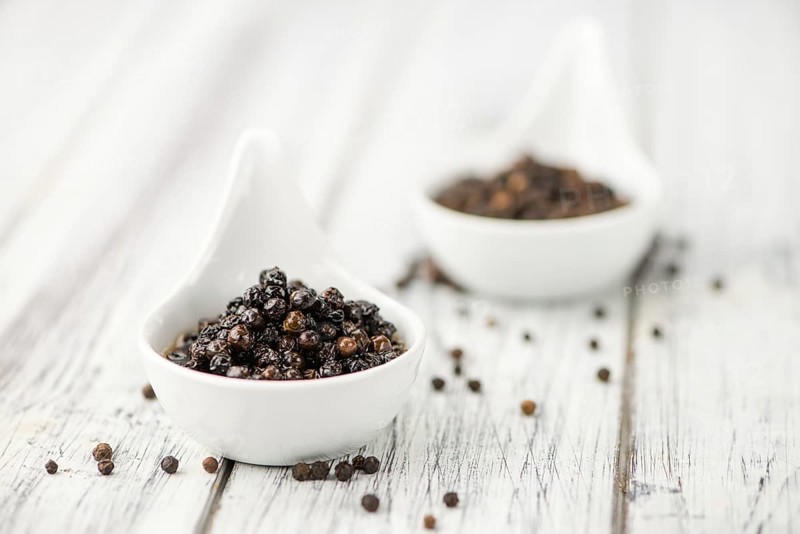 Preserved black Peppercorns on wooden background, selective focus, close-up shot
