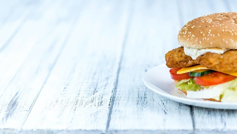 Wooden table with a fresh made Fish Burger (close-up shot, selective focus)