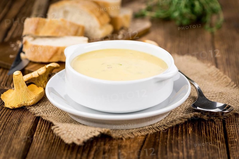 Chanterelle Soup as high detailed close-up shot on a vintage wooden table, selective focus