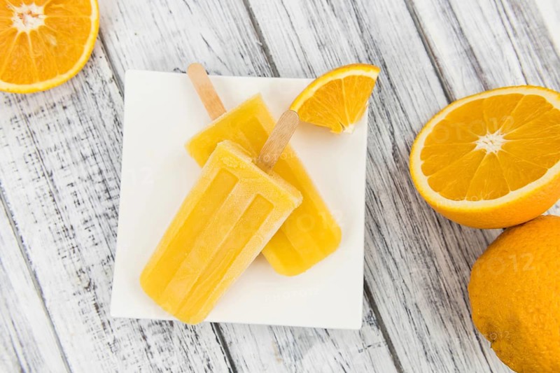 Orange Popsicles (selective focus, close-up shot) on a vintage background