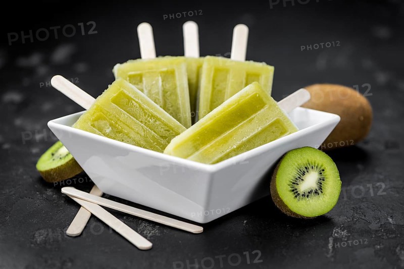 Portion of fresh made Kiwi Popsicles on a slate slab (selective focus)