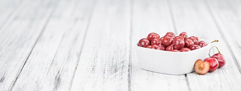 Preserved Cherries on an old wooden table as detailed close-up shot, selective focus