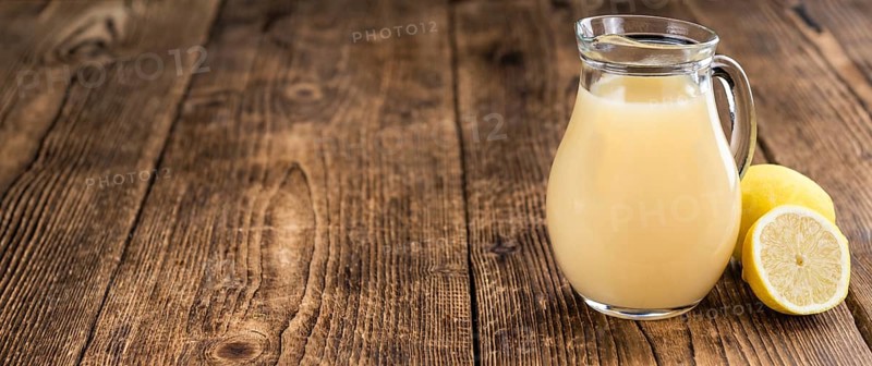 Fresh made Juice (lemon) on an old and rustic wooden table (selective focus, close-up shot)