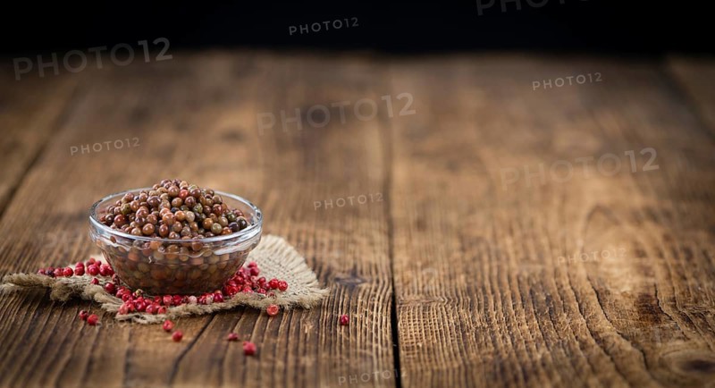 Fresh made Pink Peppercorns (preserved) on an old and rustic wooden table, selective focus, close-up shot