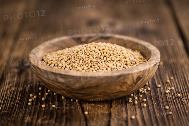 Mustard Seeds on rustic wooden background (close-up shot)