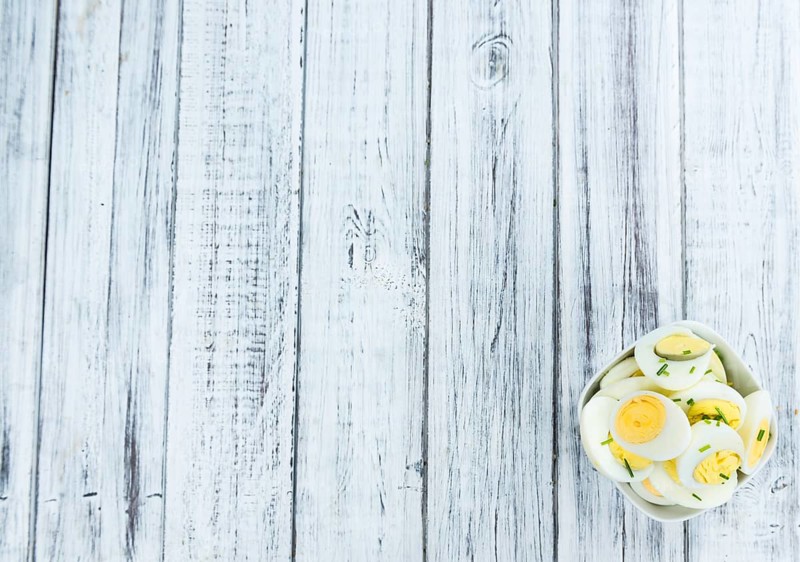 Halved Eggs on wooden background (close-up shot, selective focus)