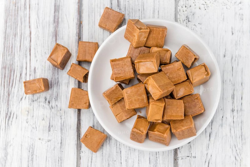 Portion of homemade Caramel on wooden background (selective focus, close-up shot)