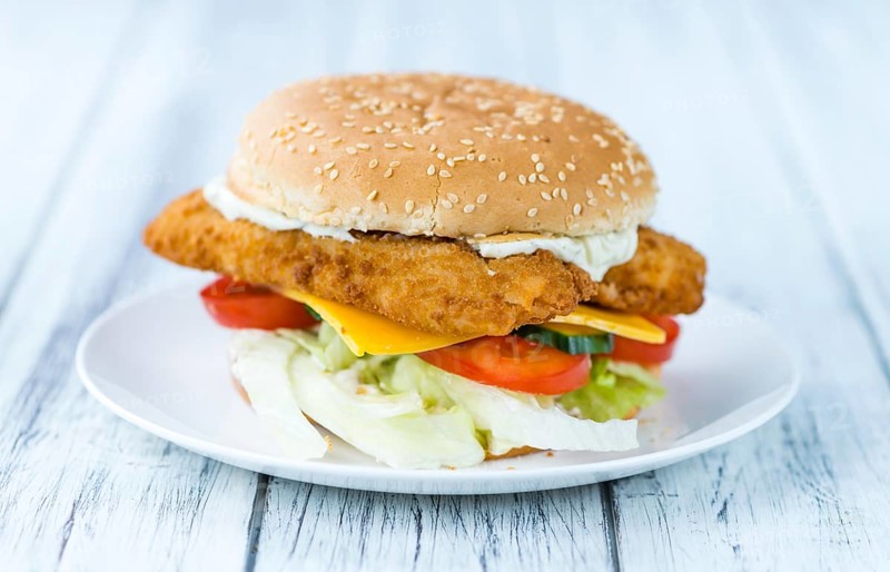 Fish Burger on wooden background (close-up shot, selective focus)