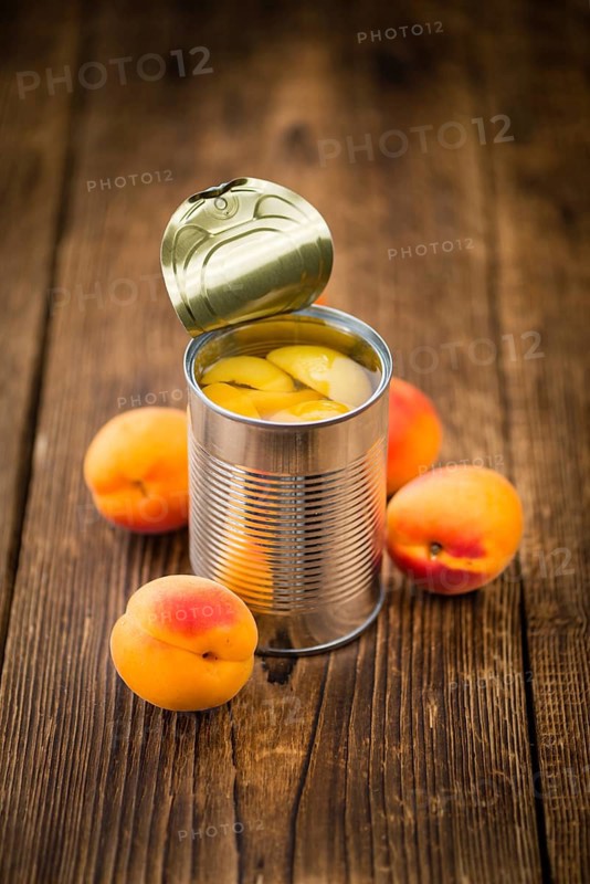 Canned Apricots on an old wooden table as detailed close-up shot (selective focus)