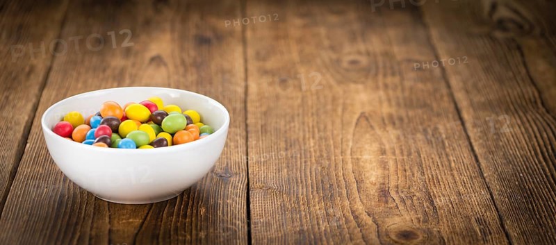 Cocolate coated Peanuts on an old wooden table as detailed close-up shot (selective focus)