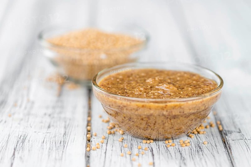 Mustard (sweet) on rustic wooden background (close-up shot)