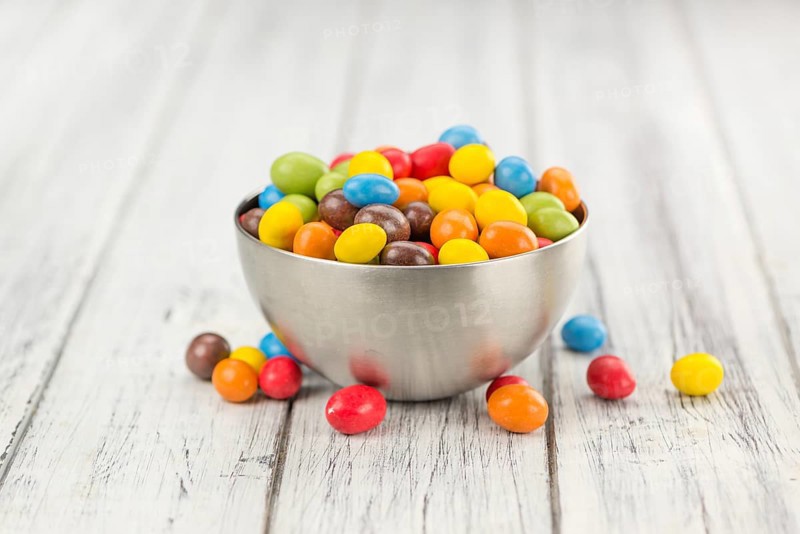 Cocolate coated Peanuts on rustic wooden background (close-up shot)