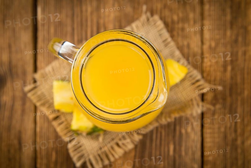Pineapple Juice as high detailed close-up shot on a vintage wooden table, selective focus