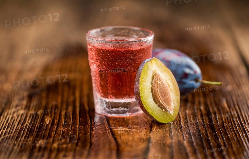 Plum Liqueur on rustic wooden background as close-up shot