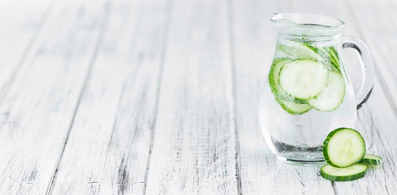 Fresh made Cucumber Water as high detailed close-up shot on a vintage wooden table, selective focus