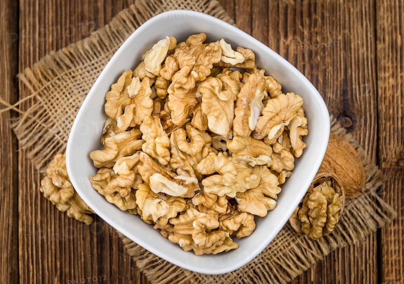 Walnuts (kernels) on an old wooden table as detailed close-up shot (selective focus)