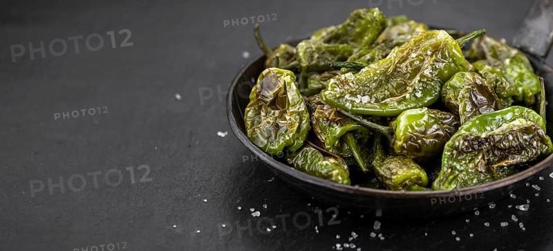 Some Pimientos de Padron on a slate slab as detailed close-up shot, selective focus