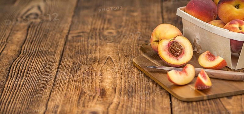Fresh Peaches as high detailed close-up shot on a vintage wooden table, selective focus