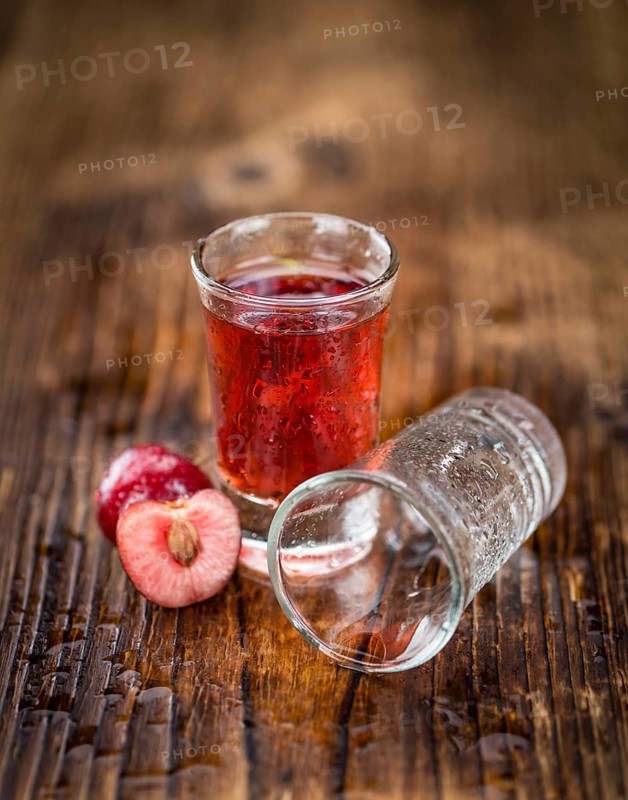 Cherry Liqueur as high detailed close-up shot on a vintage wooden table, selective focus