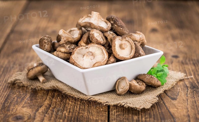 Shiitake mushrooms on an old wooden table as detailed close-up shot, selective focus