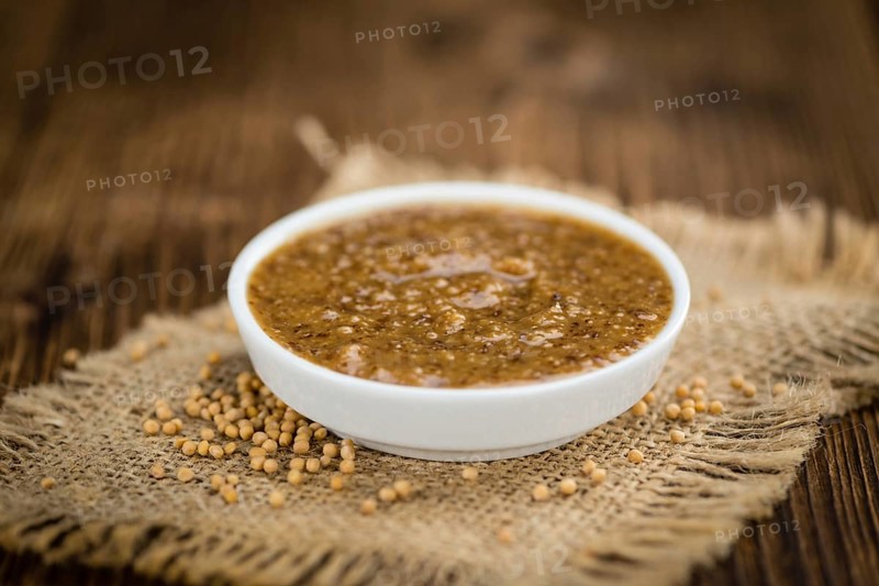 Mustard (sweet) on rustic wooden background (close-up shot)
