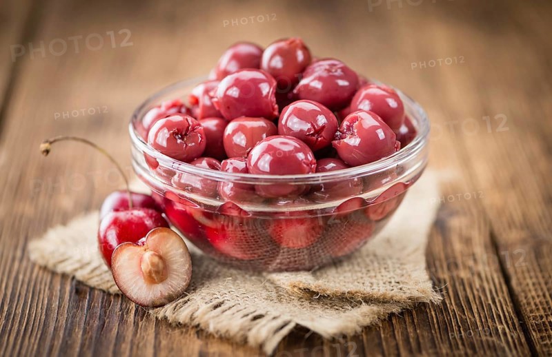 Preserved Cherries on an old wooden table as detailed close-up shot, selective focus
