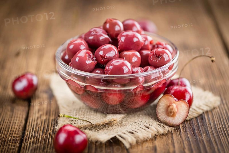 Canned Cherries as high detailed close-up shot on a vintage wooden table, selective focus