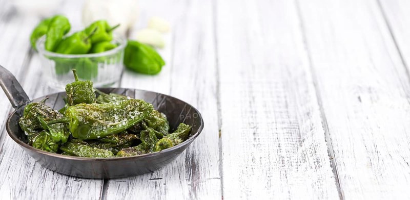 Pimientos de Padron on rustic wooden background as close-up shot