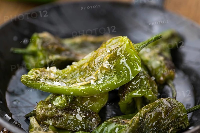 Pimientos de Padron on rustic wooden background as close-up shot