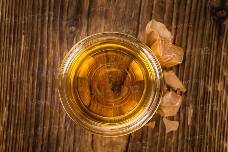 Caramel Syrup as high detailed close-up shot on a vintage wooden table (selective focus)