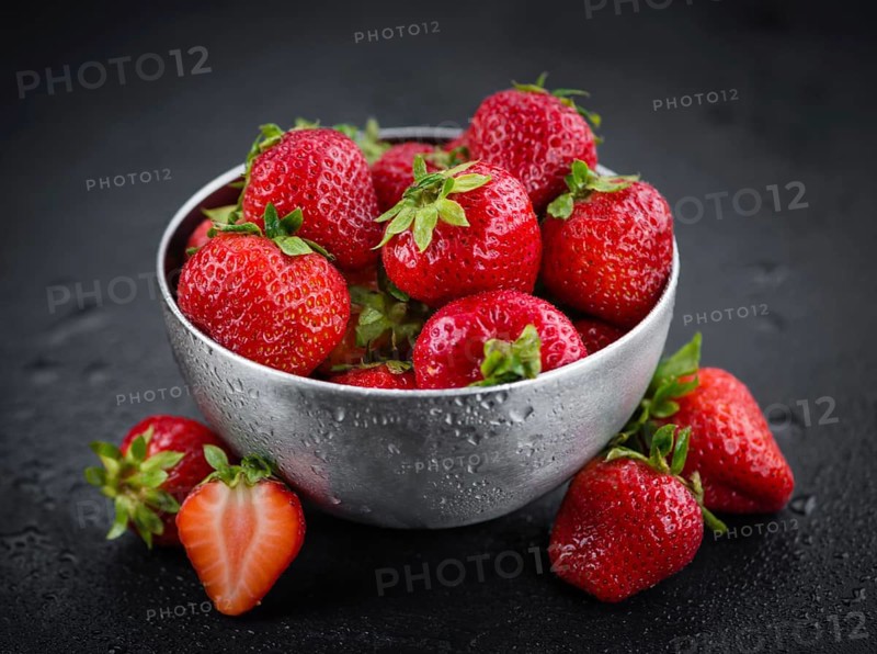 Portion of Strawberries as detailed close up shot on a slate slab, selective focus