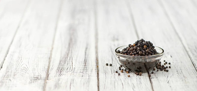 Preserved black Peppercorns on wooden background, selective focus, close-up shot