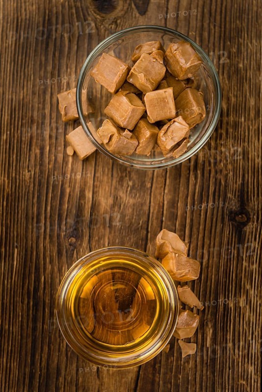Syrup (Caramel taste) on an old wooden table as detailed close-up shot (selective focus)