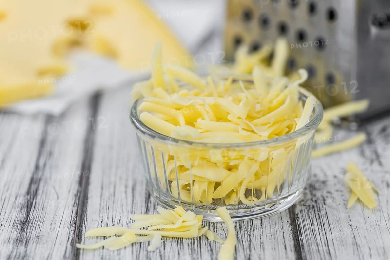 Old wooden table with grated Cheese (close-up shot)
